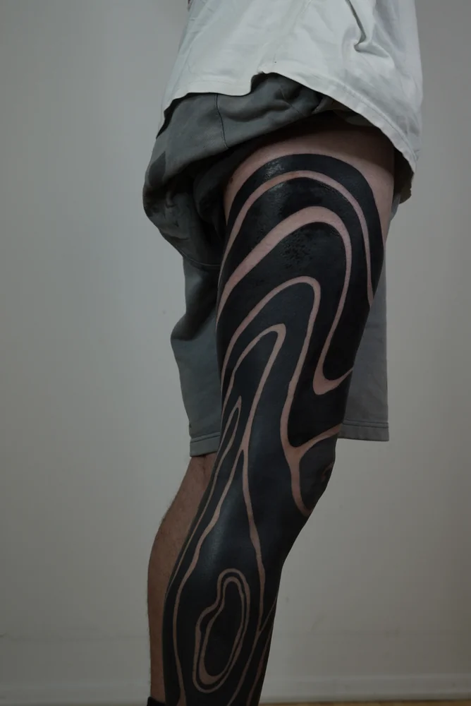 Blackout-Tattoo am Bein mit geschwungenen freien Hautlinien, Detailansicht