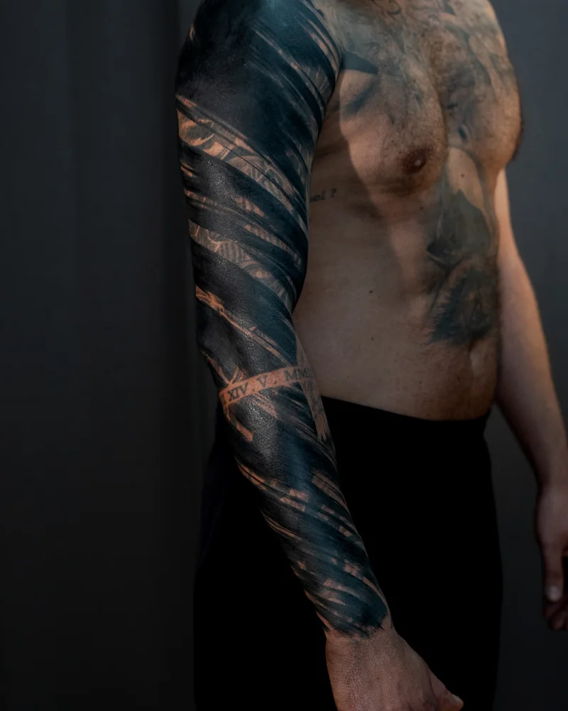 Blackwork am Arm mit breiten schwarzen Formen und diagonalen freien Linien