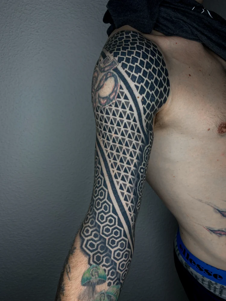 Abgeheilt: Geometrischer Arm-Sleeve mit Dreiecken, Sechsecken und diagonalen schwarzen Bändern zwischen bestehenden farbigen Motiven