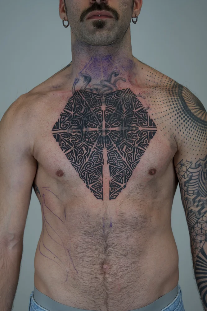 Geometrisches Mandala-Tattoo in der Brustmitte mit verschachtelten schwarzen Linien und Schablonenlinien für die Erweiterung