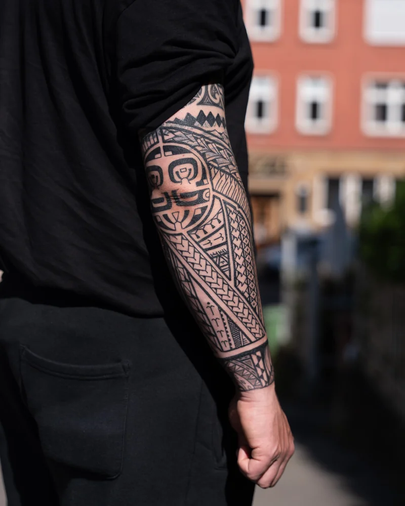 Abgeheiltes Freehand-Cover-up mit samoanisch und Marquesas-inspirierten Mustern und figurativem Rundmotiv am Arm
