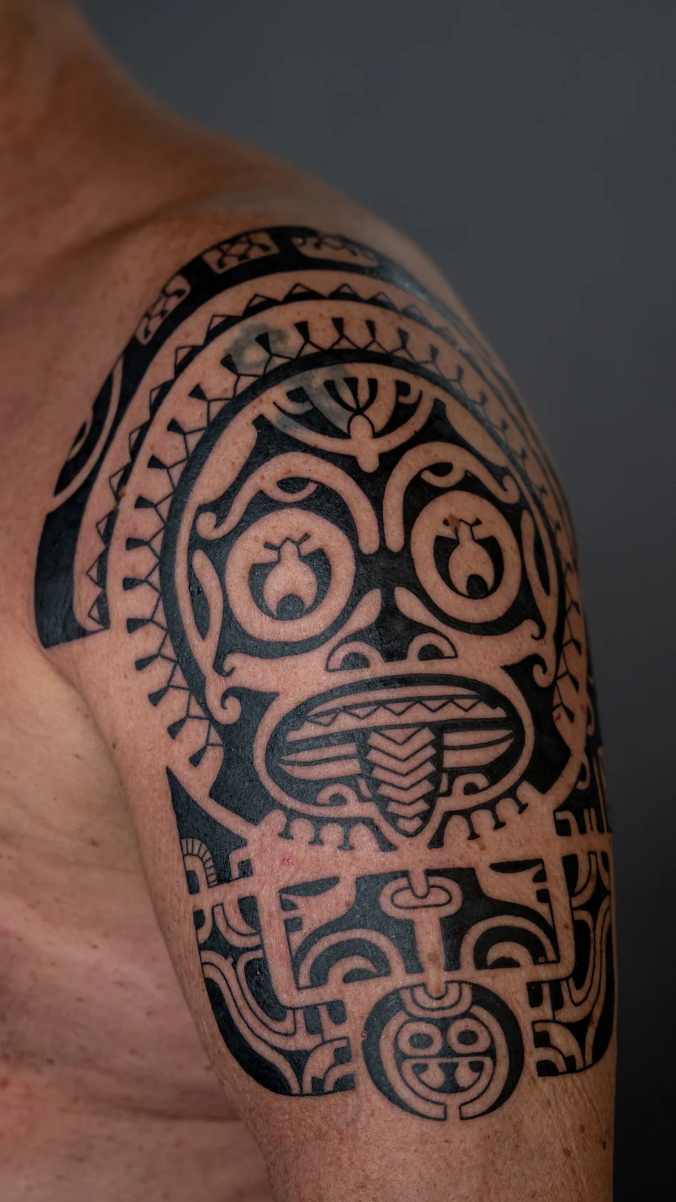 Marquesas-inspiriertes Tattoo am Oberarm mit großem figurativem Rundmotiv, Detailansicht