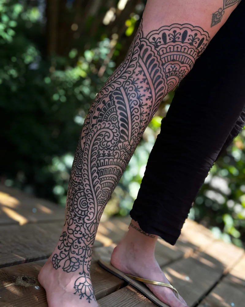 Abgeheilt: Ornamentales Beintattoo mit floralen Mustern und geschwungenen Bögen
