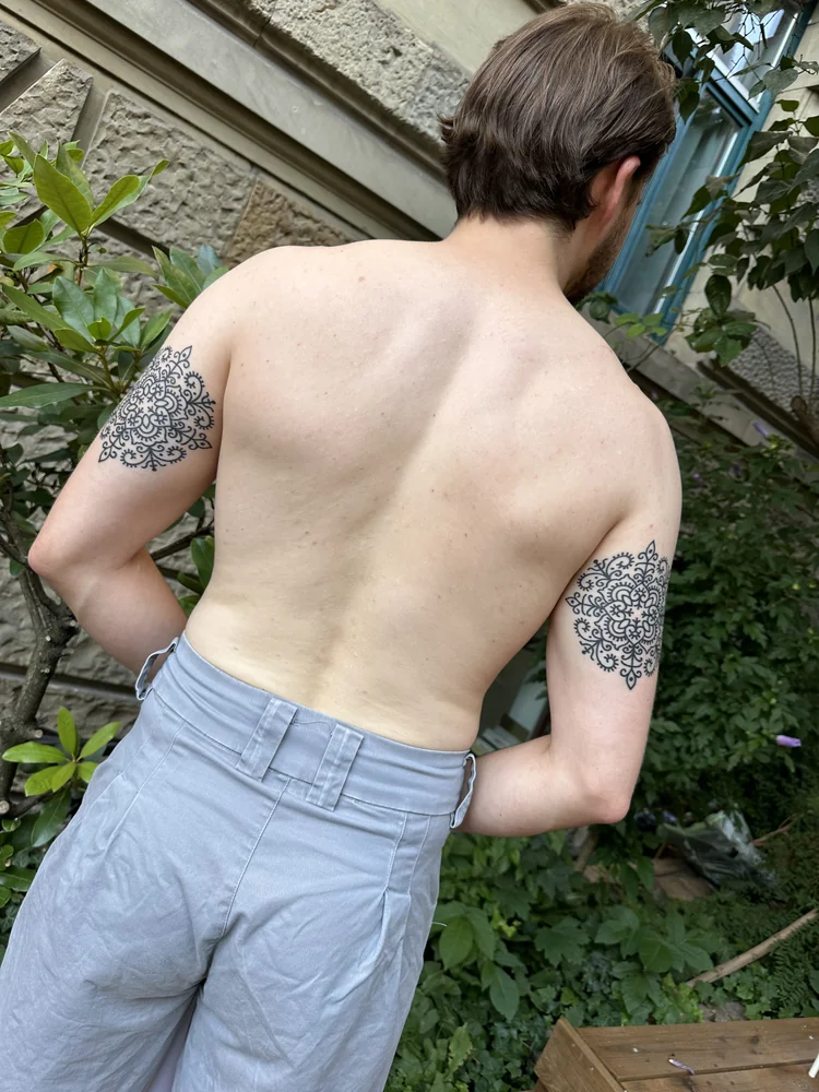 Ornamentale Mandala-Tattoos an beiden Oberarmen mit floralen Linienmotiven, Ansicht von hinten