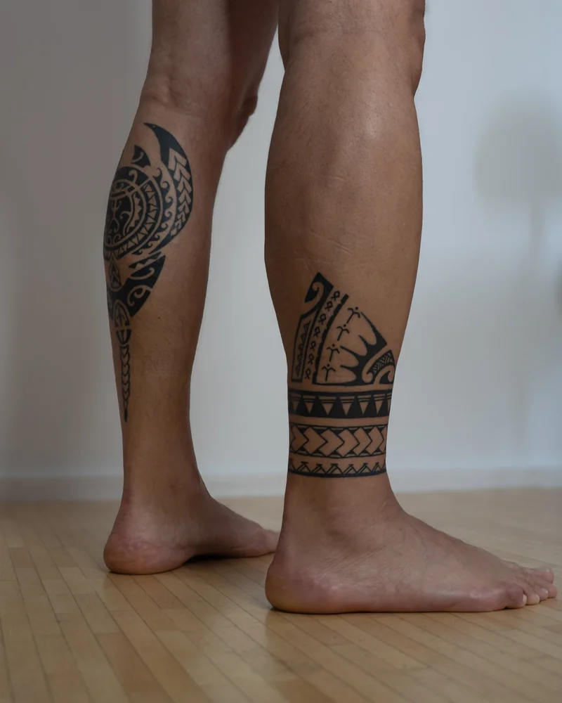 Polynesisch inspirierte Tattoos an beiden Waden mit einem Rundmotiv und geometrischen Musterbändern