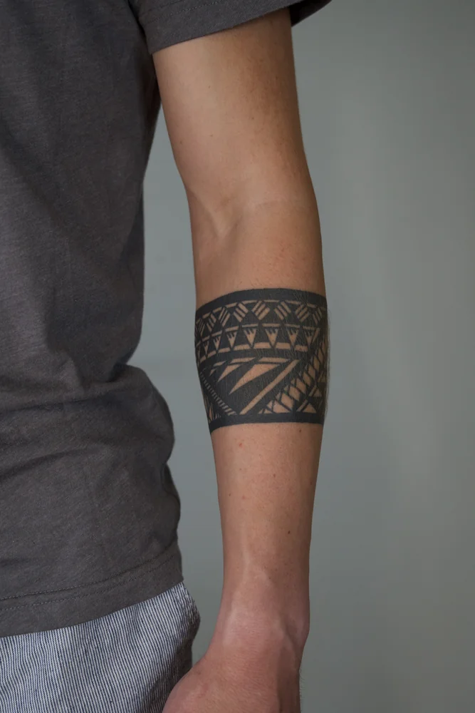 Samoanisch inspiriertes Armband-Tattoo mit geometrischen Dreiecksreihen und diagonalen Bändern